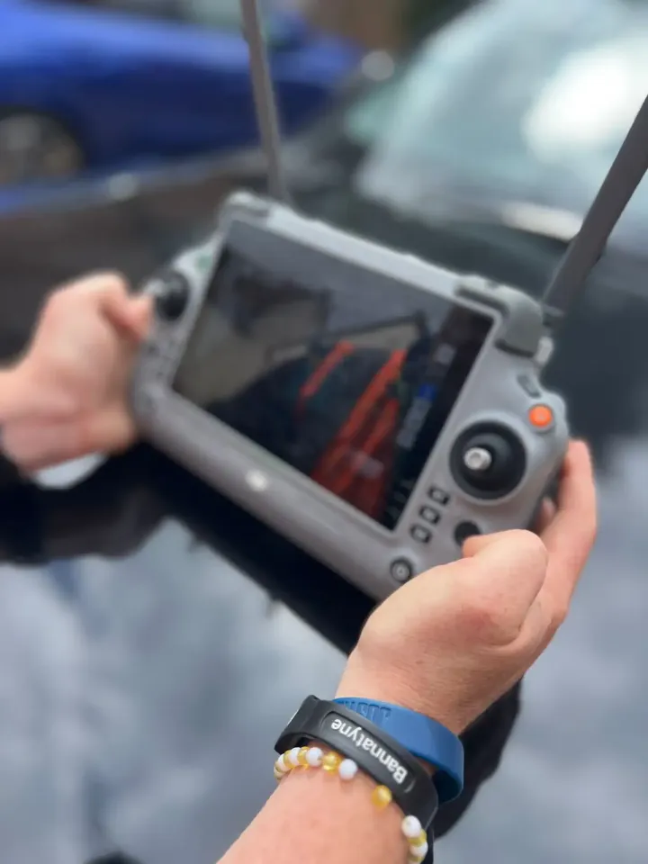 Surveyor flying a drone using a handheld controller with a live video screen