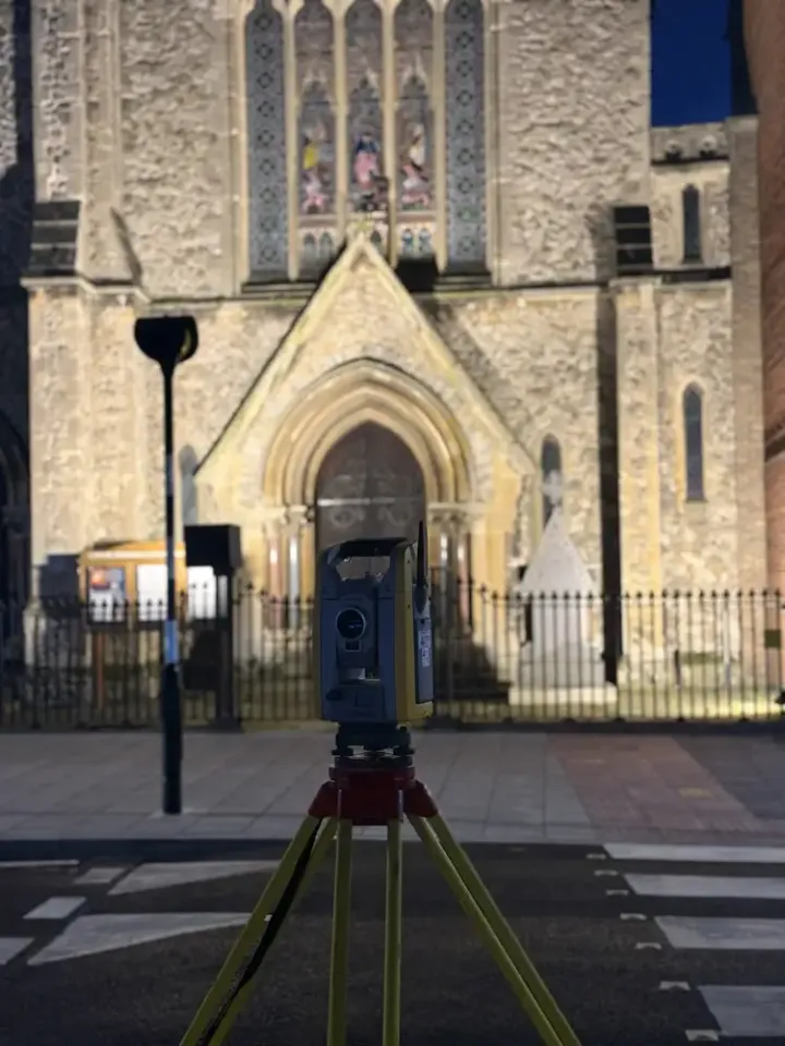 Total station set up at night in front of a historic church for a measured survey